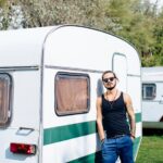 Man chilling by the vintage caravan on a sunny day.