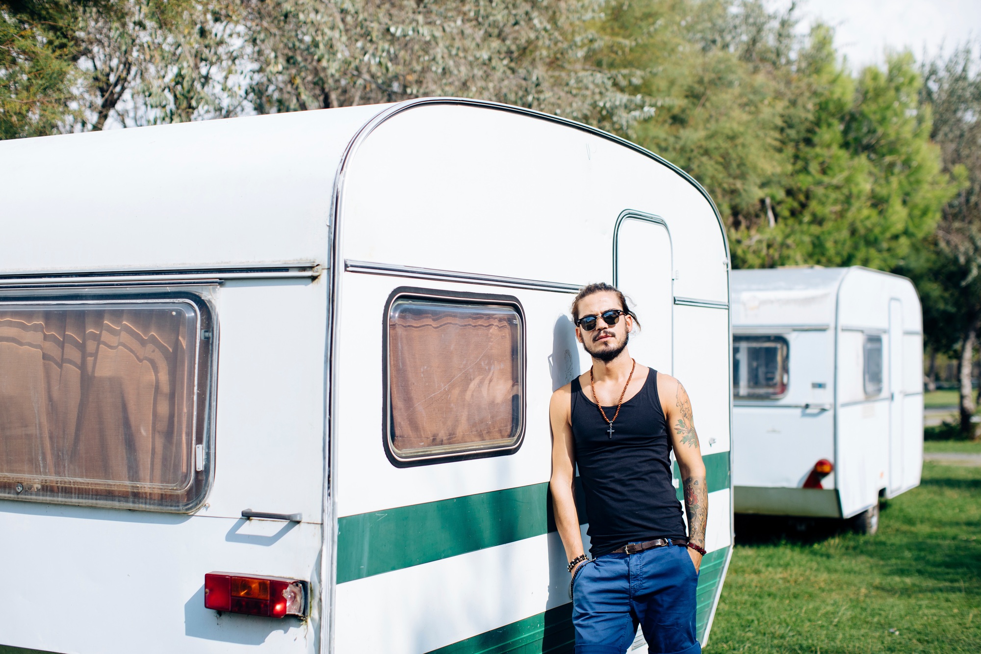Man chilling by the vintage caravan on a sunny day.